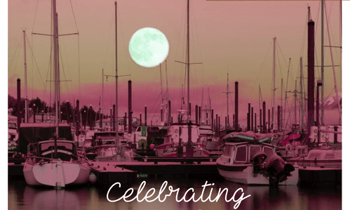 Sailboats docked in a marina under a full moon at sunset