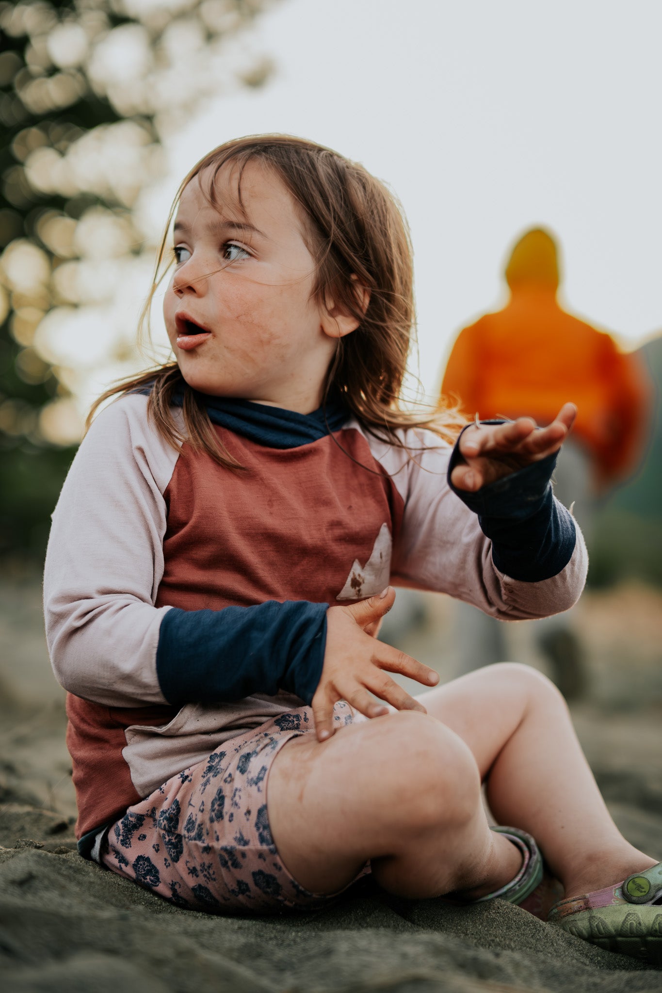 Child sitting on a sandy surface with a blurred background