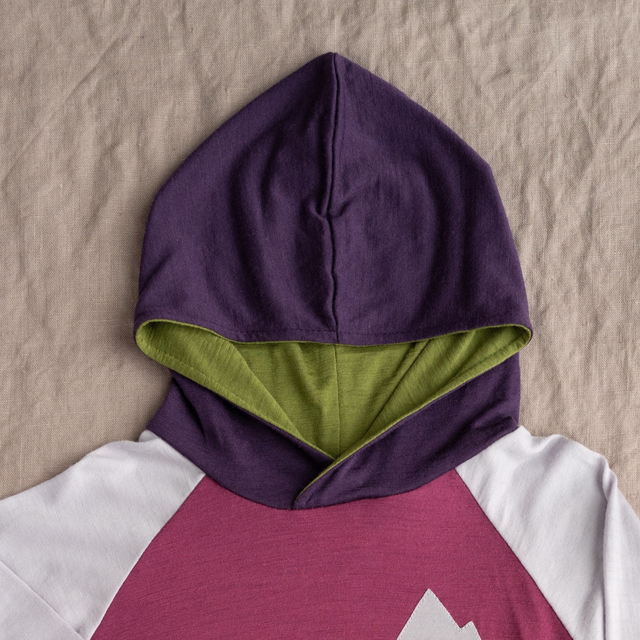 Kids’ Free Range merino wool hoodie in Fireweed, showing hood detail.