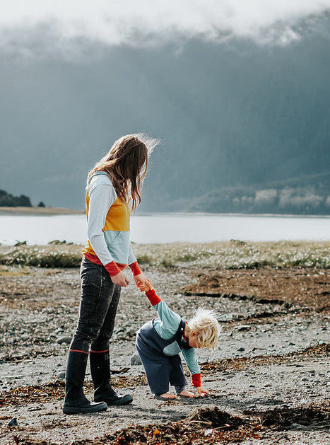 Woman and child with a dog on a beach with mountains in the background