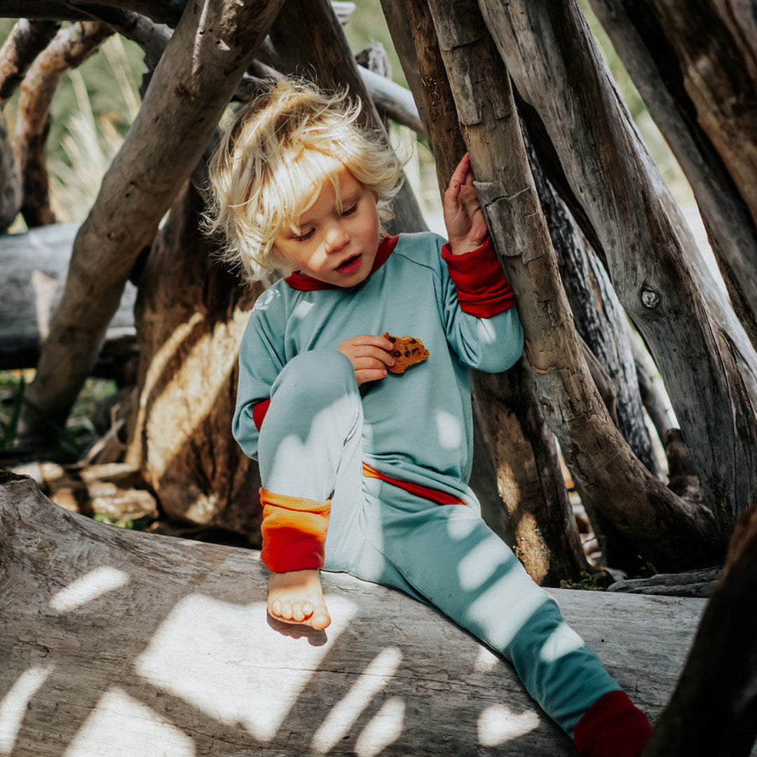 Child sitting inside a wooden fort with sunlight filtering through