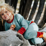 Child sitting on a rock in a natural setting in Essential Crew and Legging set in Birch Sky