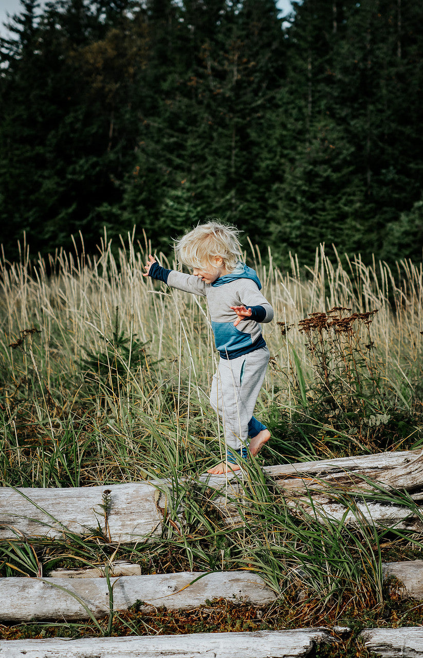 Child playing on logs in a forest setting